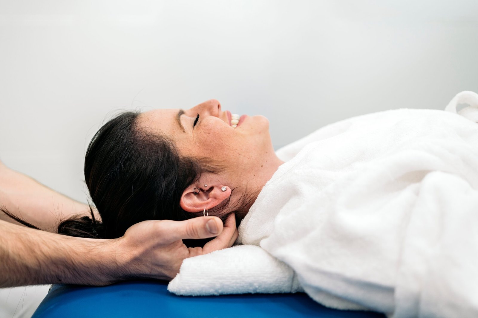 relaxed,woman,enjoying,neck,massage,while,lying,in,stretcher.